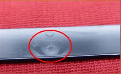 Injection molded plastic part showing a surface void caused by trapped air or internal gas